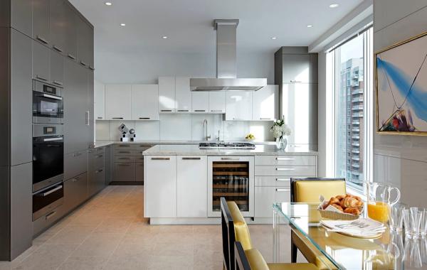 grande cuisine armoires en gris anthracite et blanc îlot central blanc espace de travail en marbre table en verre chaises jaunes cuisine armoires en gris anthracite et blanc
