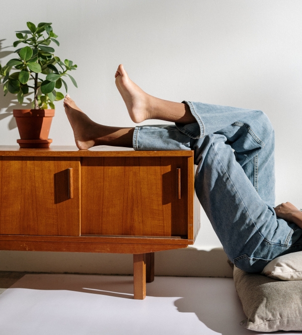 femme habillée en jeans loose avec pieds sur une commode bois