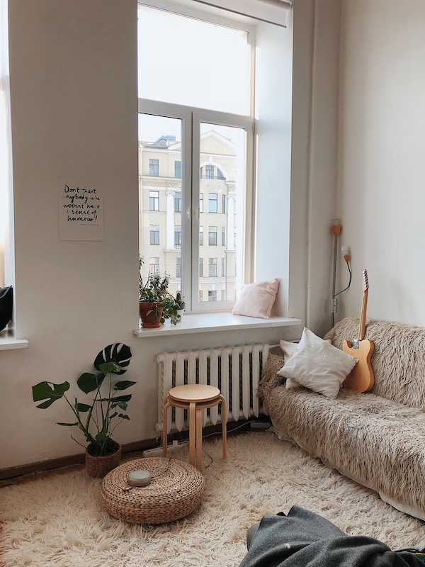 canapé-cosy-tapis-berbere-pouf-tricoté-tables-basses-gigognes-bois-murs-blancs déco salon cocooning blanc avec pouf tressé, tables gigognes bois, plante verte