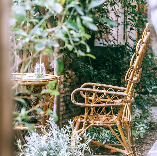 table-et-chaises-tressées-et-vegetation-autour-plantes-vertes-de-jardin-patio deco jardin avec des chaises tressés et vegetation verte autour