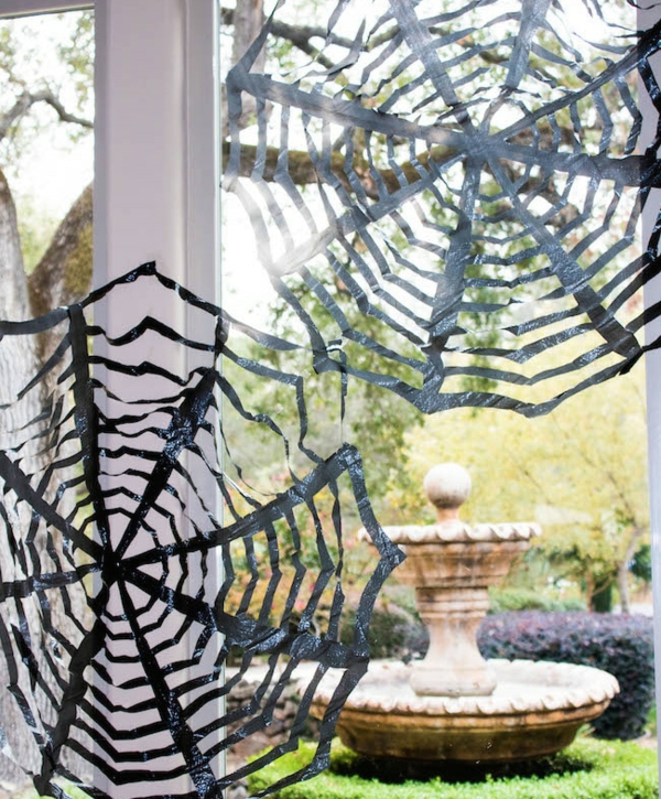 idée de déco extérieure pour halloween toile d'araignée faite en sac poubelle coupé en lanières