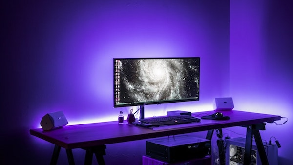 lumières néon de couleur bleue dans une chambre à coucher design avec grand bureau et grand écran pc