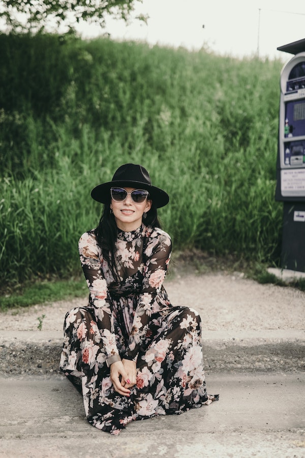 robe noire manche longue transparente avec des fleurs pivoines, accessoirisée de chapeau et lunettes de soleil
